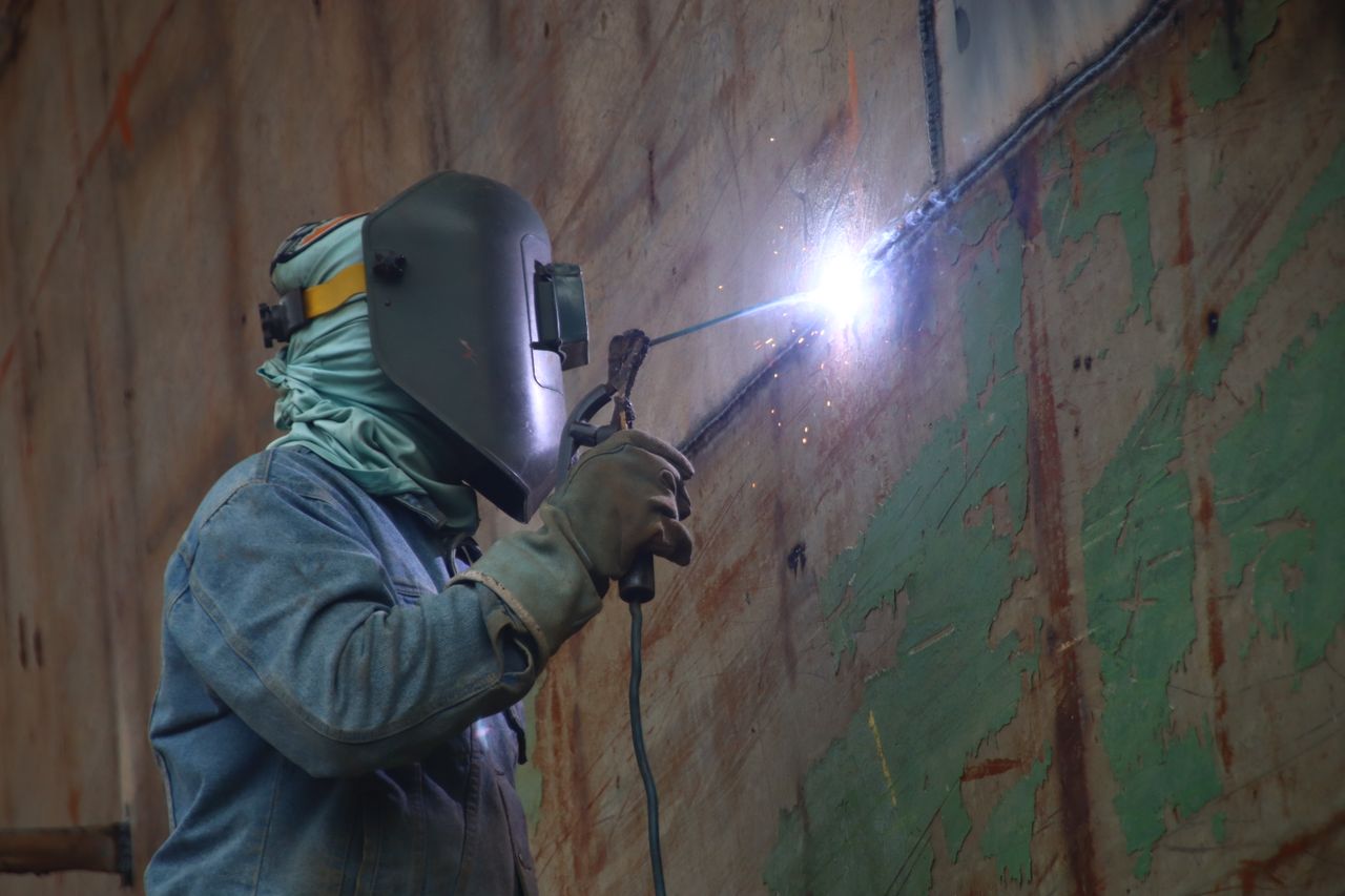 A welder works in a Keraniganj shipyard, highlighting industrial labor's skilled techniques.